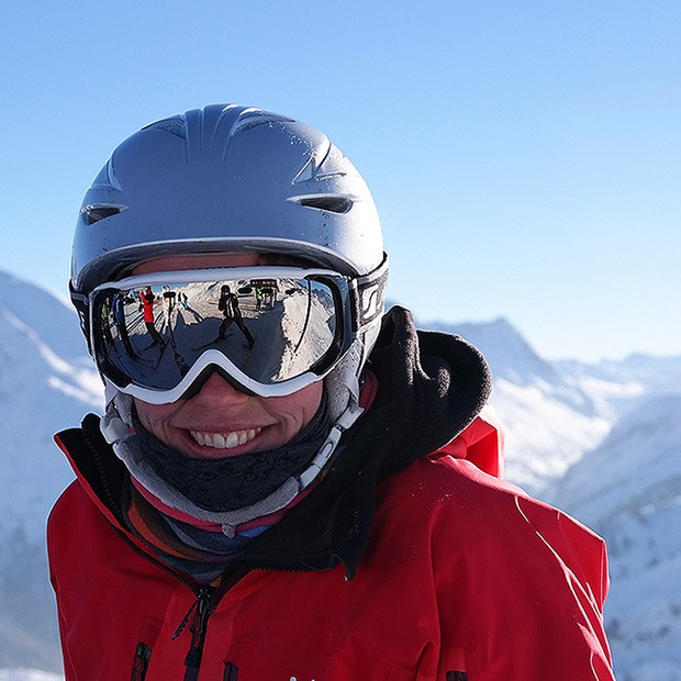 Adult smiling in snow gear, in the snow-capped mountains