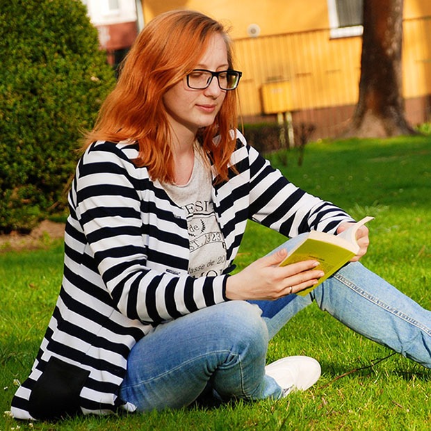 Adult woman reading a book outside with black glasses