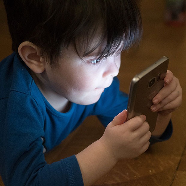 Young boy looking at a phone's screen in the dark