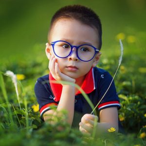 young boy with blue circular frames outside