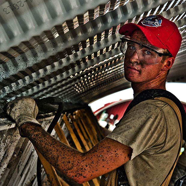 Man covered in mud at work with safety glasses on