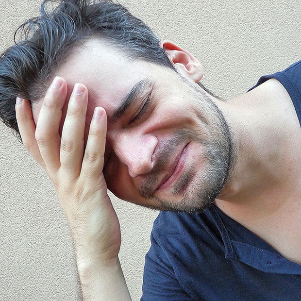 Young man with a headache, feeling his forehead and with a face of despair